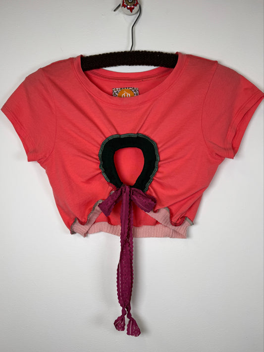 Pink crop tee shirt with dark green trim and purple ribbons on a white background